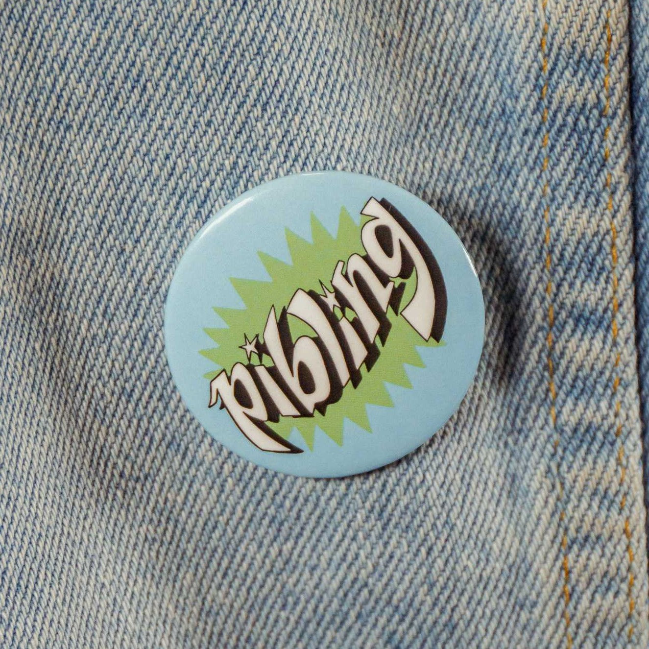 An aquamarine blue pin with text that says "pibling" with a green spiky design in the background.