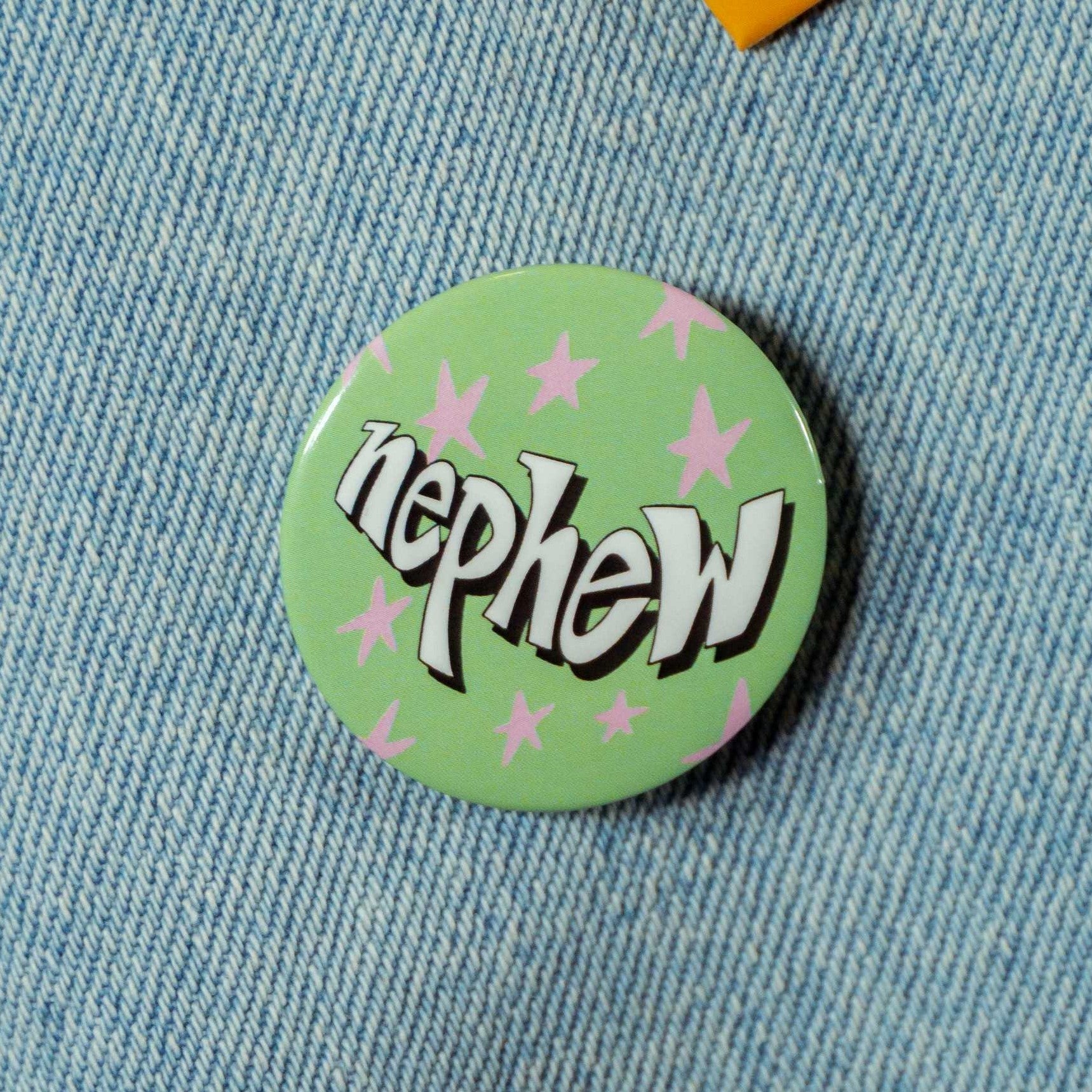 Green circular pin with pink stars with text that says "nephew"