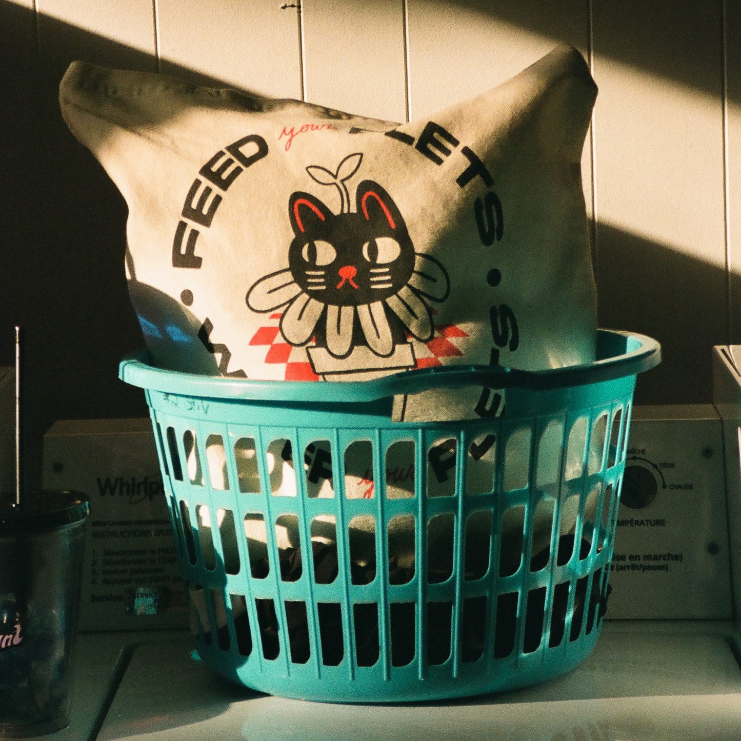 Natural canvas tote bag with text that says "feed your plets, water your plets" in black. The text surrounds a hand-drawn image of a cat in a flowerpot.